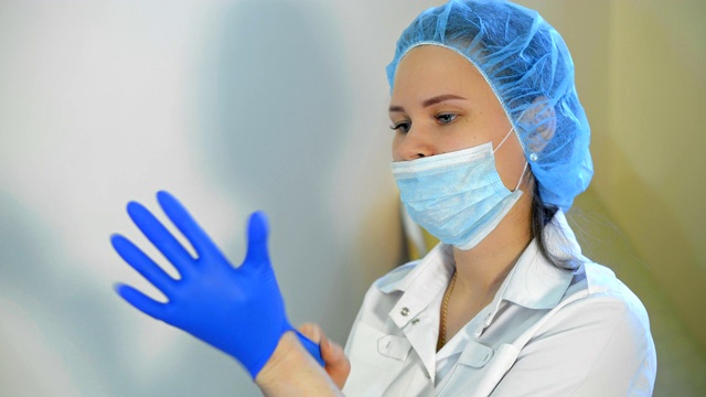 年轻女护士或医生戴着外科口罩站在房间里的肖像。视频素材