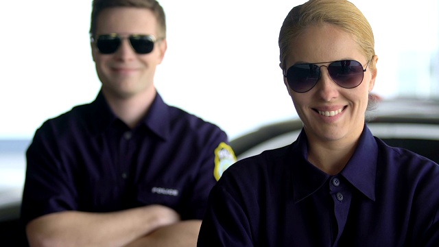 友好的警察戴着眼镜看着镜头微笑着，同事们视频素材