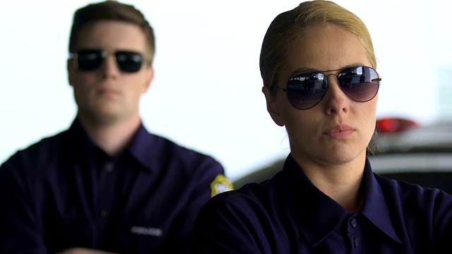 坚定的男警员和女警员戴着眼镜看着镜头，队伍视频素材