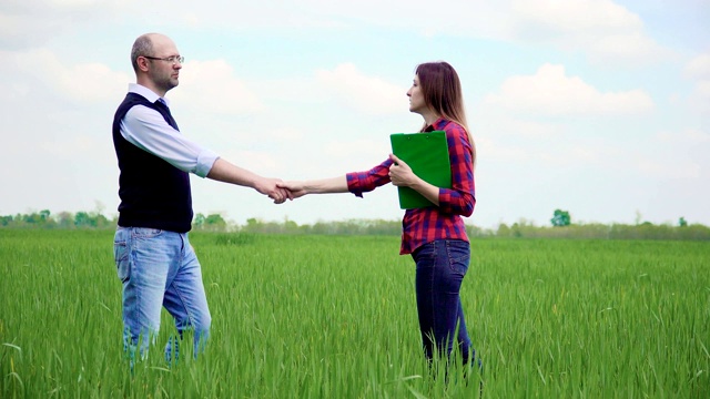 两名农民在麦田里握手，用文件签署合作协议视频下载