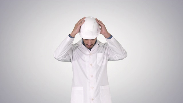 一名身穿白袍的阿拉伯工程师戴着安全帽，将安全帽放在渐变背景上视频下载
