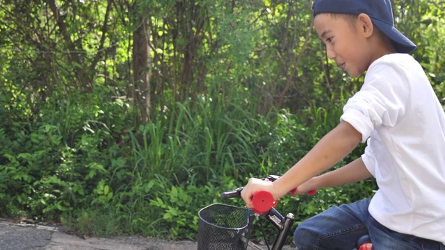 亚洲小男孩在花园里学骑和摔倒自行车，学骑自行车视频下载