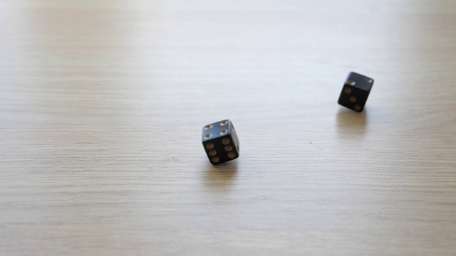 用一副黑色骰子在桌子上以慢动作滚动4和2视频素材