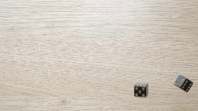 用慢动作在桌子上滚动一对黑色骰子视频素材