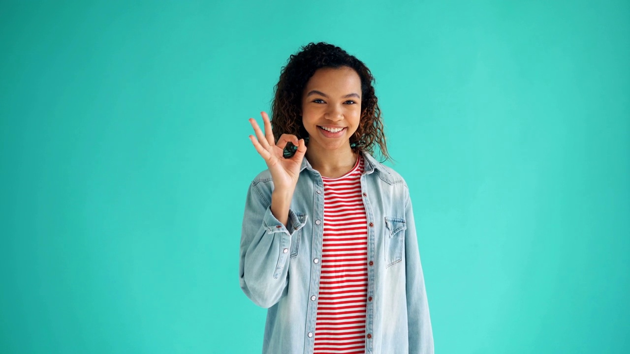 高兴的非洲裔美国女孩显示OK手势的肖像看着相机视频素材