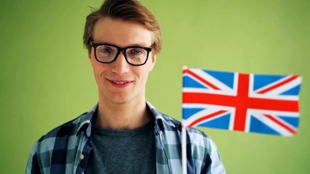 特写慢动作的微笑的家伙在风中挥舞着英国国旗视频下载
