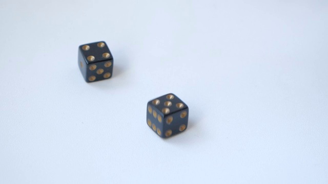 用一对黑色骰子在一张白色的桌子上用慢动作滚动一个5和一个4视频素材