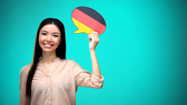 微笑的女孩举着德国国旗演讲泡泡，学习语言，旅行想法视频下载