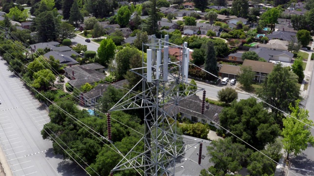 在加州库比蒂诺一个阳光明媚的日子里，一架载有通信设备的无人机正在高压输电塔周围飞行。视频素材