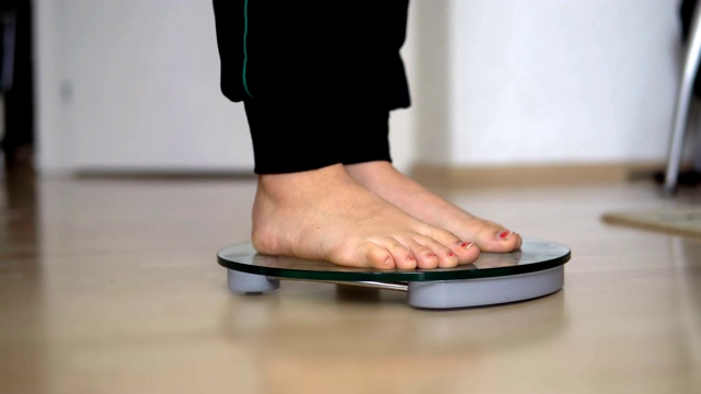 女性光脚配体重秤在木地板上，减肥节食视频素材