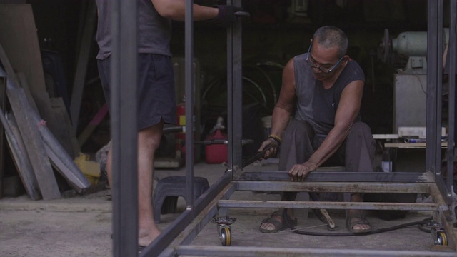 二人工人在家焊接金属的慢镜头。视频下载