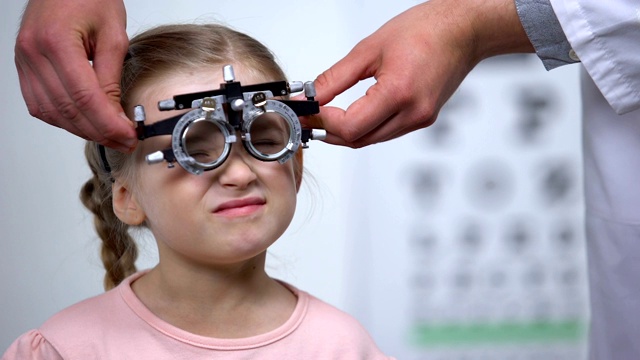 医生戴着光学试验架对儿童进行诊断近视、视力模糊视频素材