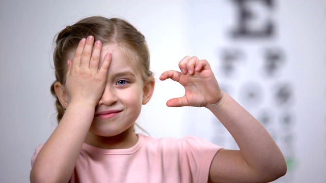 小女孩闭眼，从视力表上显示大小或体征，视力诊断视频素材