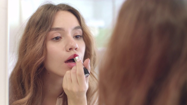 漂亮的女人用口红在浴室镜子前化妆视频素材