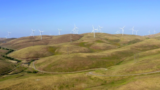 鸟瞰高压线，输电塔和风力涡轮机在一个阳光明媚的一天在北加州的田地。电力工业和自然环境的概念。视频素材