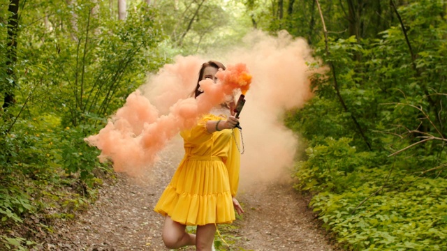 快乐的女人踏着彩色烟雾穿过森林视频素材