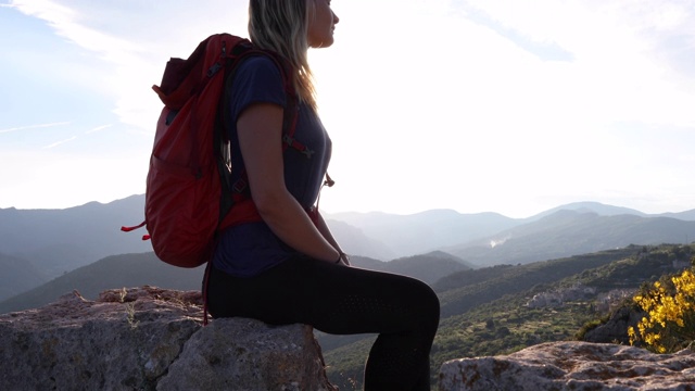 女性徒步旅行者在岩石山顶放松视频下载