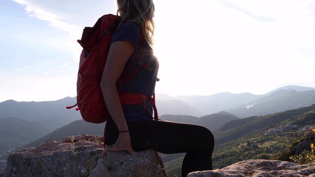 女性徒步旅行者在岩石山顶放松视频素材