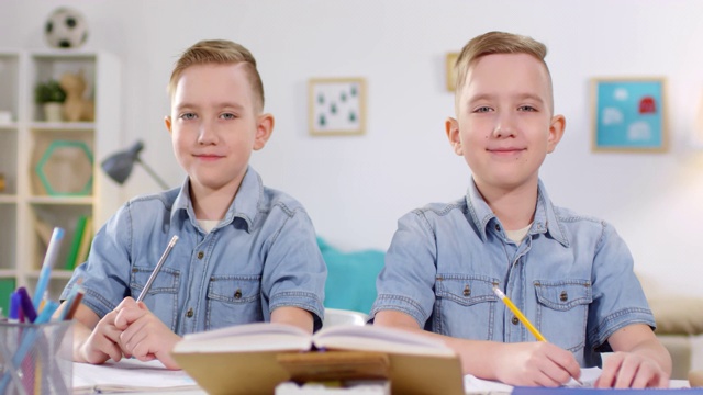 10岁的白种双胞胎在学习和摆姿势拍照视频下载