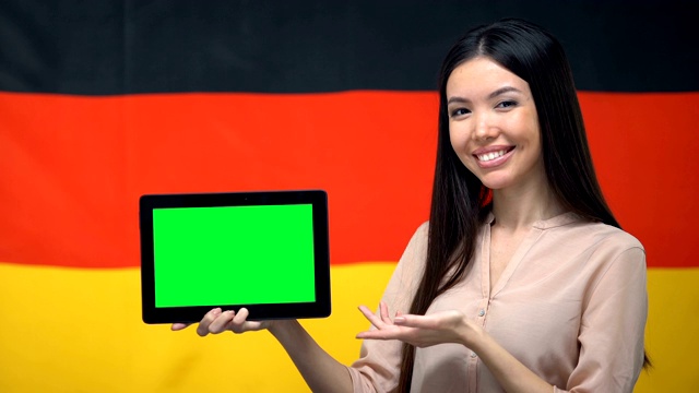 女孩拿着绿色屏幕的平板电脑，背景是德国国旗，移民视频下载