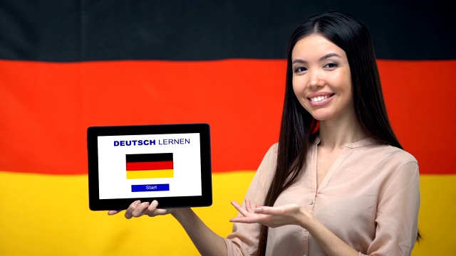 女士手持平板与学习德语应用程序，德国国旗的背景，教育视频下载