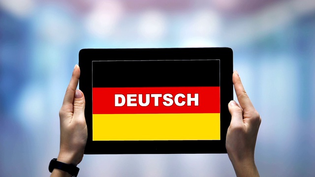 女性手握平板电脑，用德语单词对抗国旗，在线应用视频下载