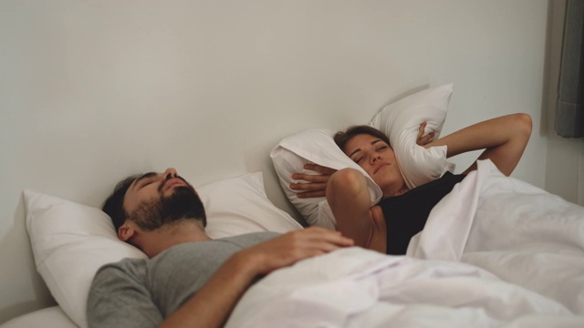 夫妻打鼾问题的概念，女人有问题，她的丈夫睡在床上打鼾视频购买