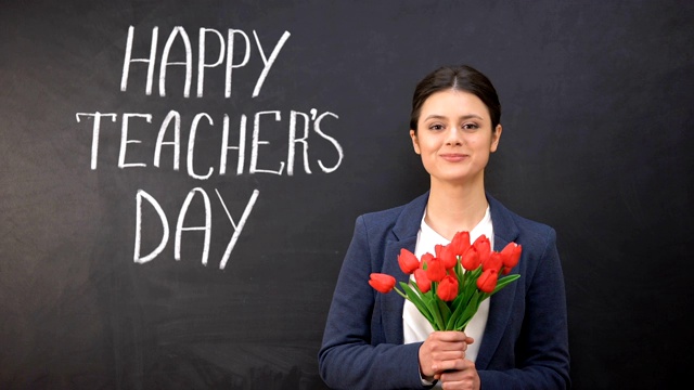 教师节快乐写在黑板上，微笑的女士拿着郁金香站在旁边视频下载