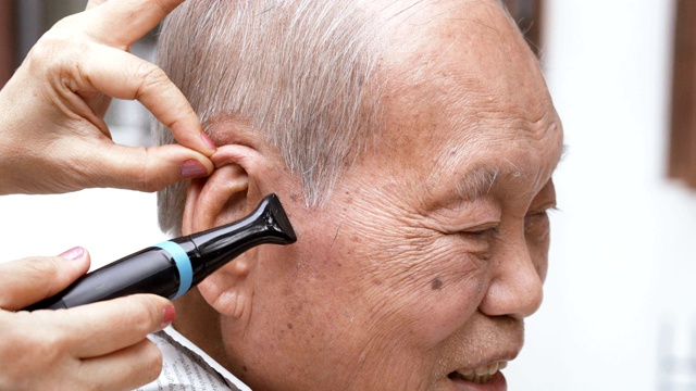 微笑的亚洲老人正在修剪头发视频素材
