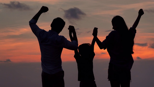 一家人在海滩上散步欣赏日落的剪影。假期——iStock视频素材