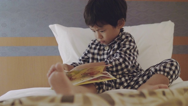 亚洲小男孩晚上在床上看书。视频素材