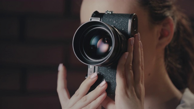 美丽的女人使用复古相机。在摄影棚工作的女摄影师视频素材