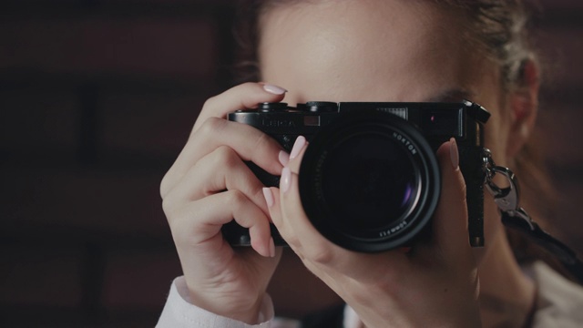 年轻的女摄影师在摄影棚里用相机拍照视频素材
