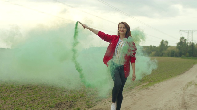 迷人的女人走在彩色烟雾中的田野视频素材
