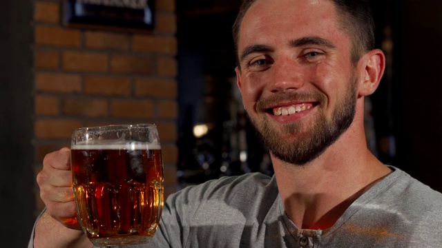 快乐的男人拿着啤酒对着镜头微笑视频下载