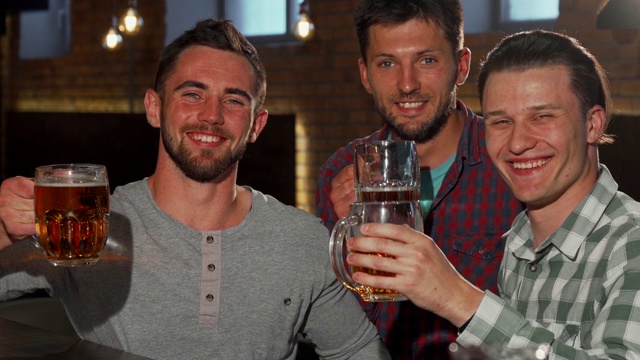 一群朋友在酒吧里举着啤酒杯对着镜头微笑视频下载