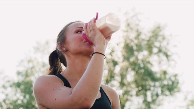 女人休息和喝蛋白质奶昔后，她的运动视频下载