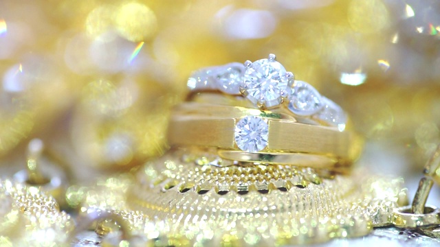 微距拍摄的结婚戒指与金色纹理的背景。视频下载