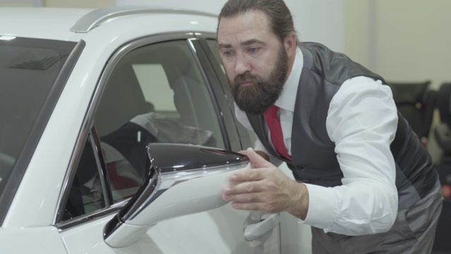 肖像吸引可爱自信的胡子商人在一个商务西装检查新购买的汽车从汽车经销商。视频下载