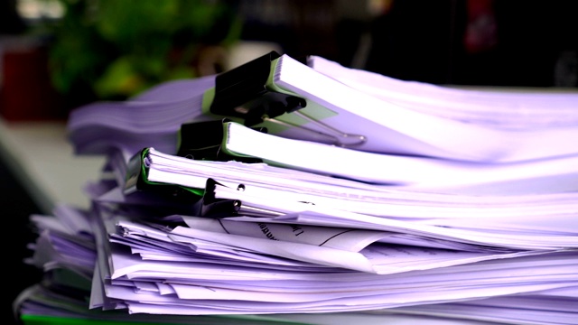 在泰国大学教师学校的办公室里，堆放着未完成的文件、报告和文件。杂乱堆放的文件、评估、法律文件夹在工作场所的概念视频素材