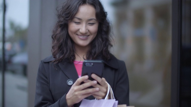 一名年轻女子在购物时使用手机视频素材