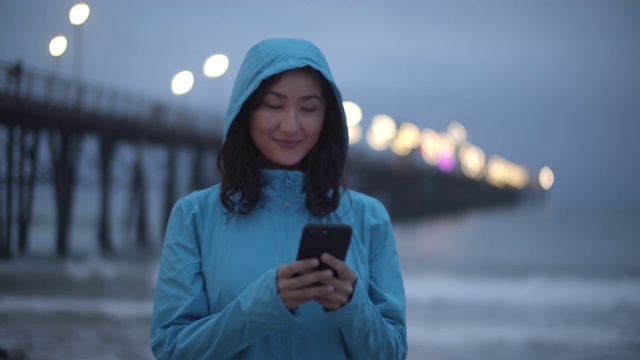一个年轻女人晚上在沙滩上玩手机视频素材