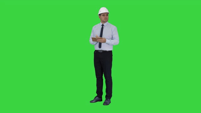 戴着头盔，穿着正装的男人四处张望，并在绿屏上做笔记视频素材