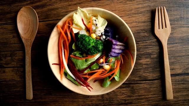 用手捏紧混合着五颜六色蔬菜的木碗放在桌上，素食者食用健康的有机食品，有利于减肥和控制体重视频下载