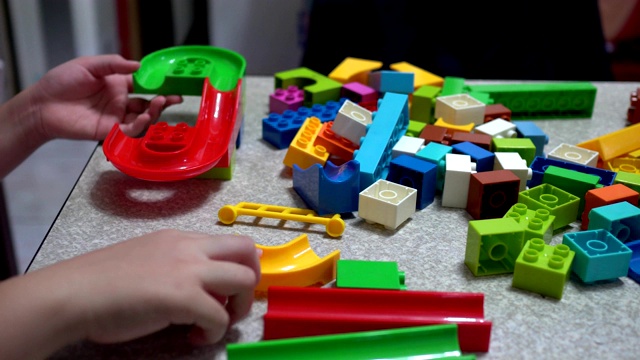 小孩子在室内玩许多五颜六色的塑料玩具。视频下载