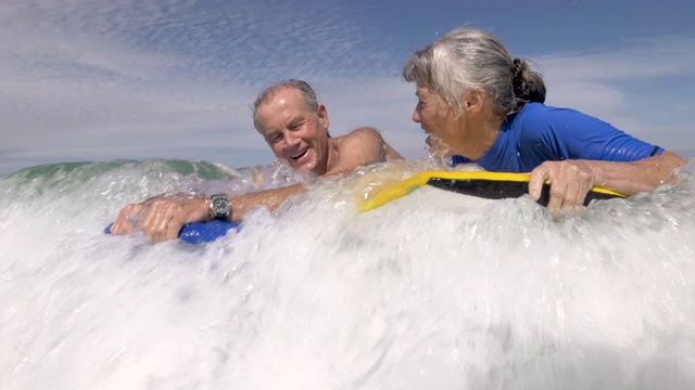一对活跃的老年情侣一起在海滩上玩滑板视频下载
