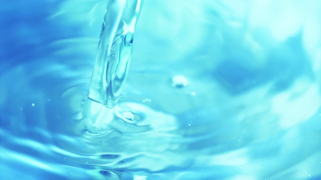 把水倒进透明的蓝色水坑，在近距离和缓慢的动作中产生波浪和涟漪。视频下载