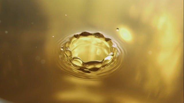 在近距离和慢镜头中，水珠在一个金色的水坑上激起涟漪视频素材