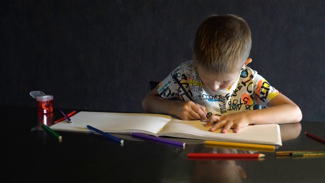 一个六岁的孩子用彩色铅笔画画。视频素材