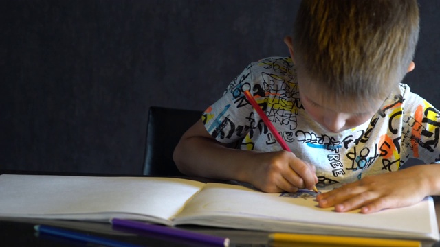 一个六岁的孩子用彩色铅笔画画。视频素材